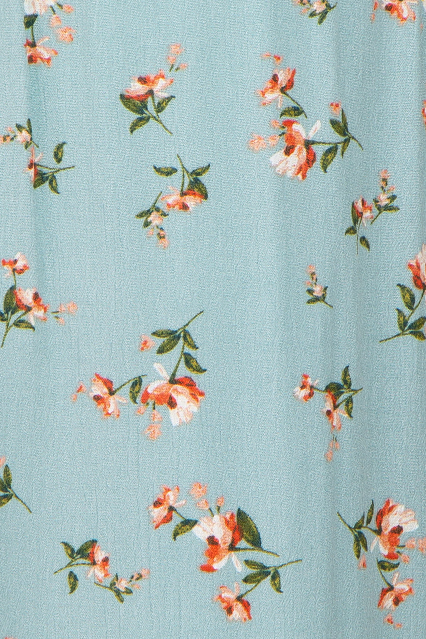 Close-up of light blue fabric with a small orange and white floral print and green leaves
