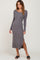 woman wearing a long sleeve grey ribbed midi dress with a side slit and black sandals