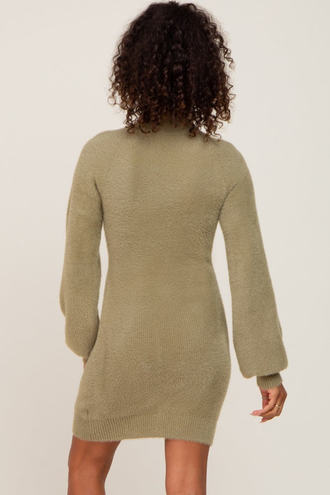back view of a woman with curly hair wearing a sage green fuzzy knit mini dress with long balloon sleeves