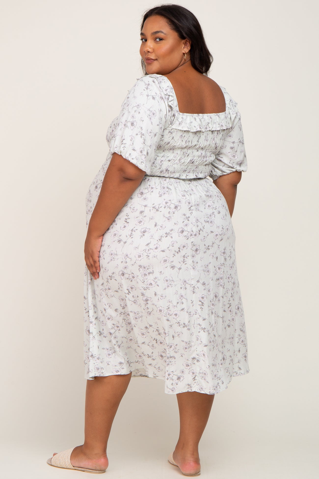 Plus size woman wearing a white floral smocked midi dress with puff sleeves and ruffle detail