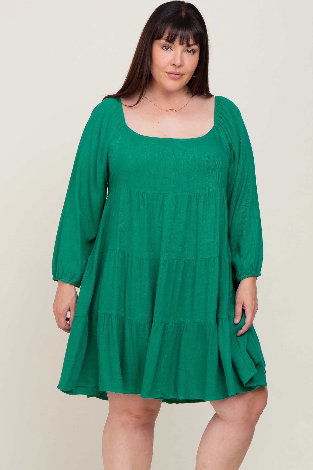 woman wearing a green tiered swing dress with long sleeves and a square neckline, styled for plus size