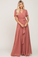 Woman wearing a mauve short sleeve wrap maxi dress with swiss dot texture and waist tie