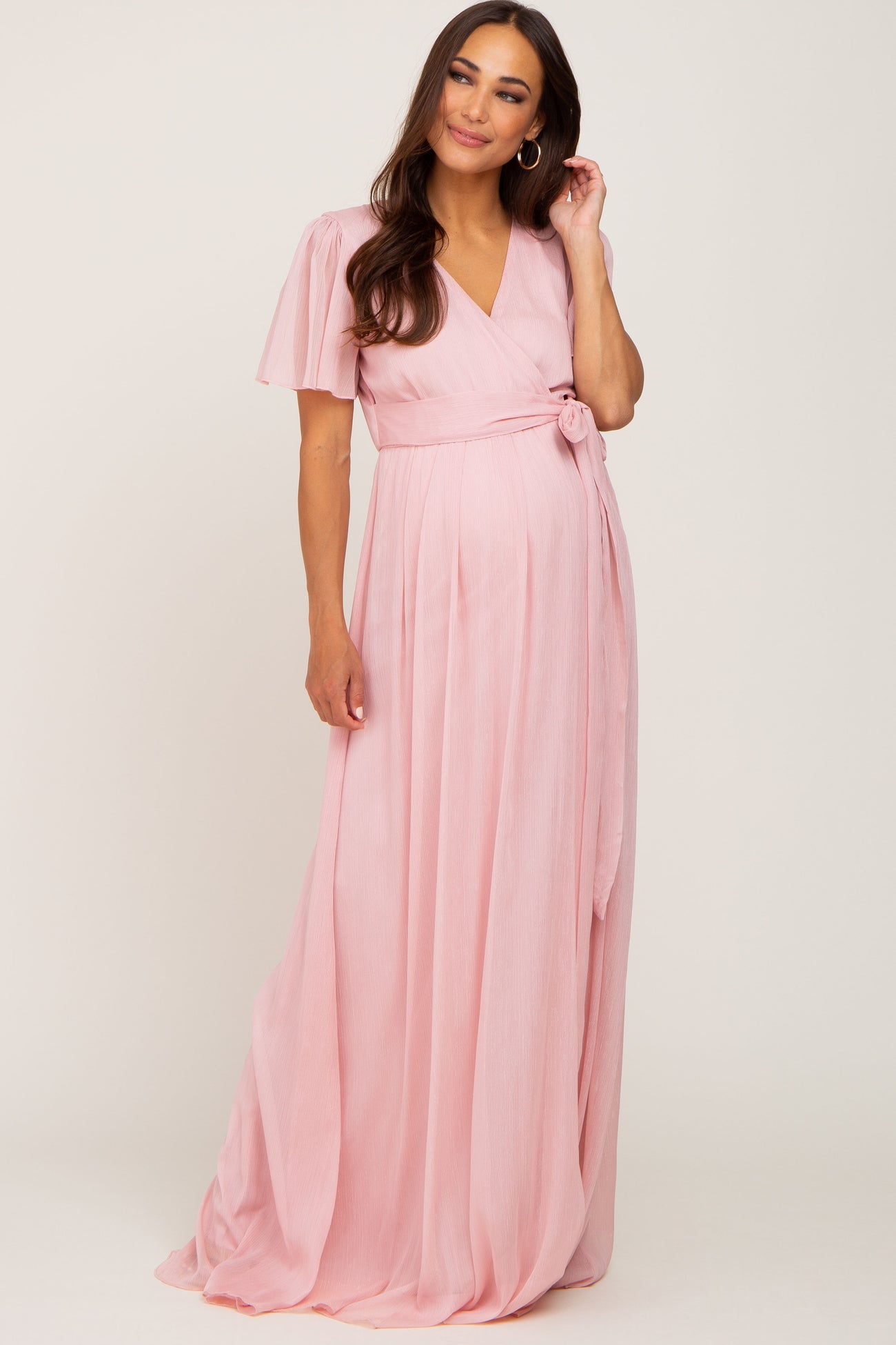 pregnant woman wearing a light pink short sleeve wrap maternity maxi dress with a waist tie