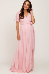 pregnant woman wearing a light pink short sleeve wrap maternity maxi dress with a waist tie