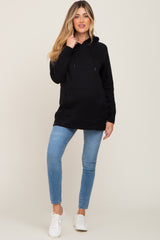 woman wearing a black maternity hoodie and blue skinny jeans with white sneakers
