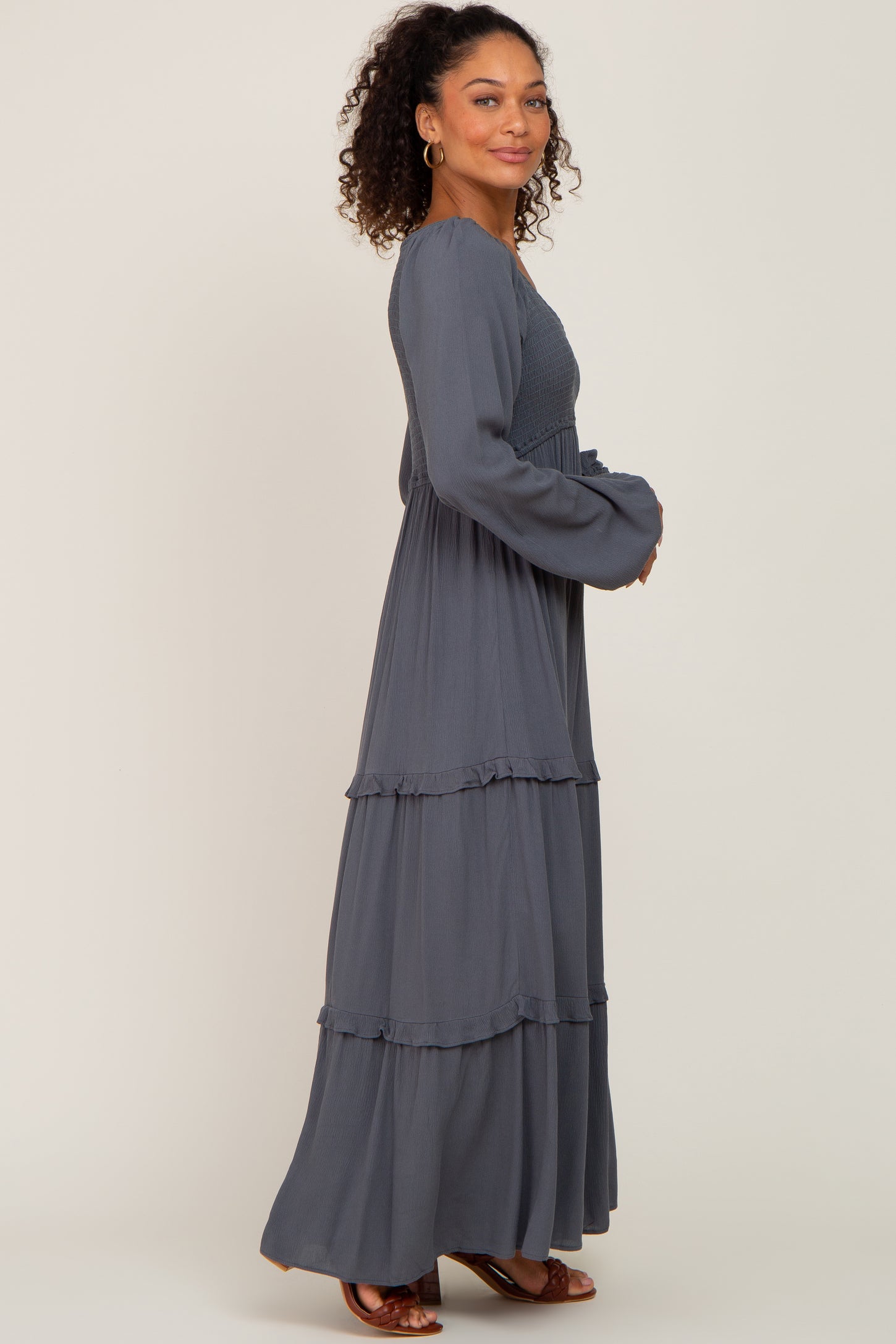 woman wearing a charcoal grey long sleeve tiered maxi dress with smocked bodice and ruffled details