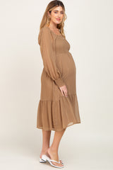 Pregnant woman wearing a brown long sleeve maternity dress with gold pinstripes and smocked bodice