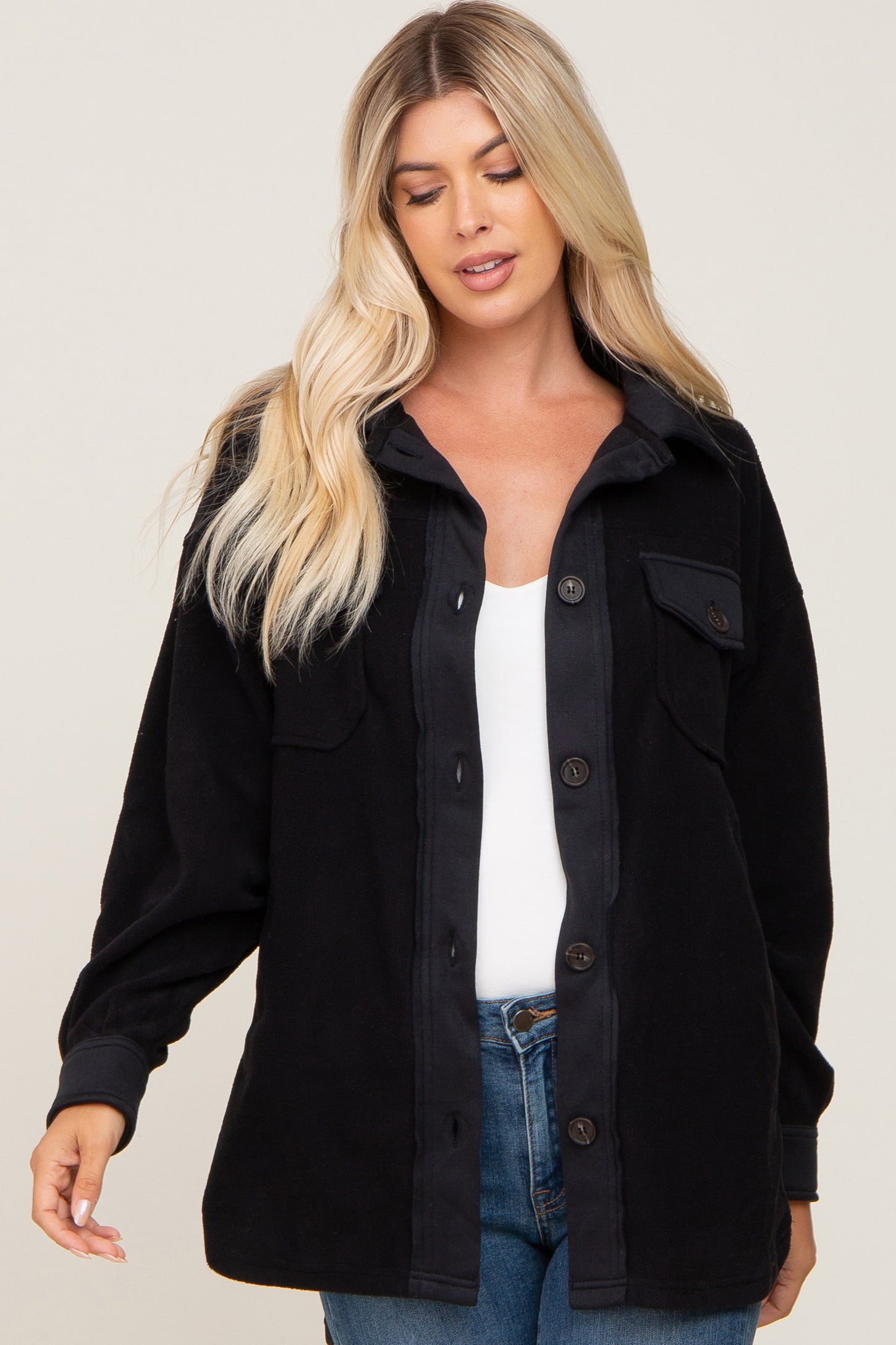 Woman wearing a black button-down fleece shacket over a white top and blue jeans
