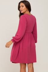 Woman wearing a long sleeve magenta pink babydoll dress with a gathered waist and puff sleeves