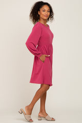 Woman wearing a long sleeve magenta pink babydoll dress with pockets and tan block heel sandals