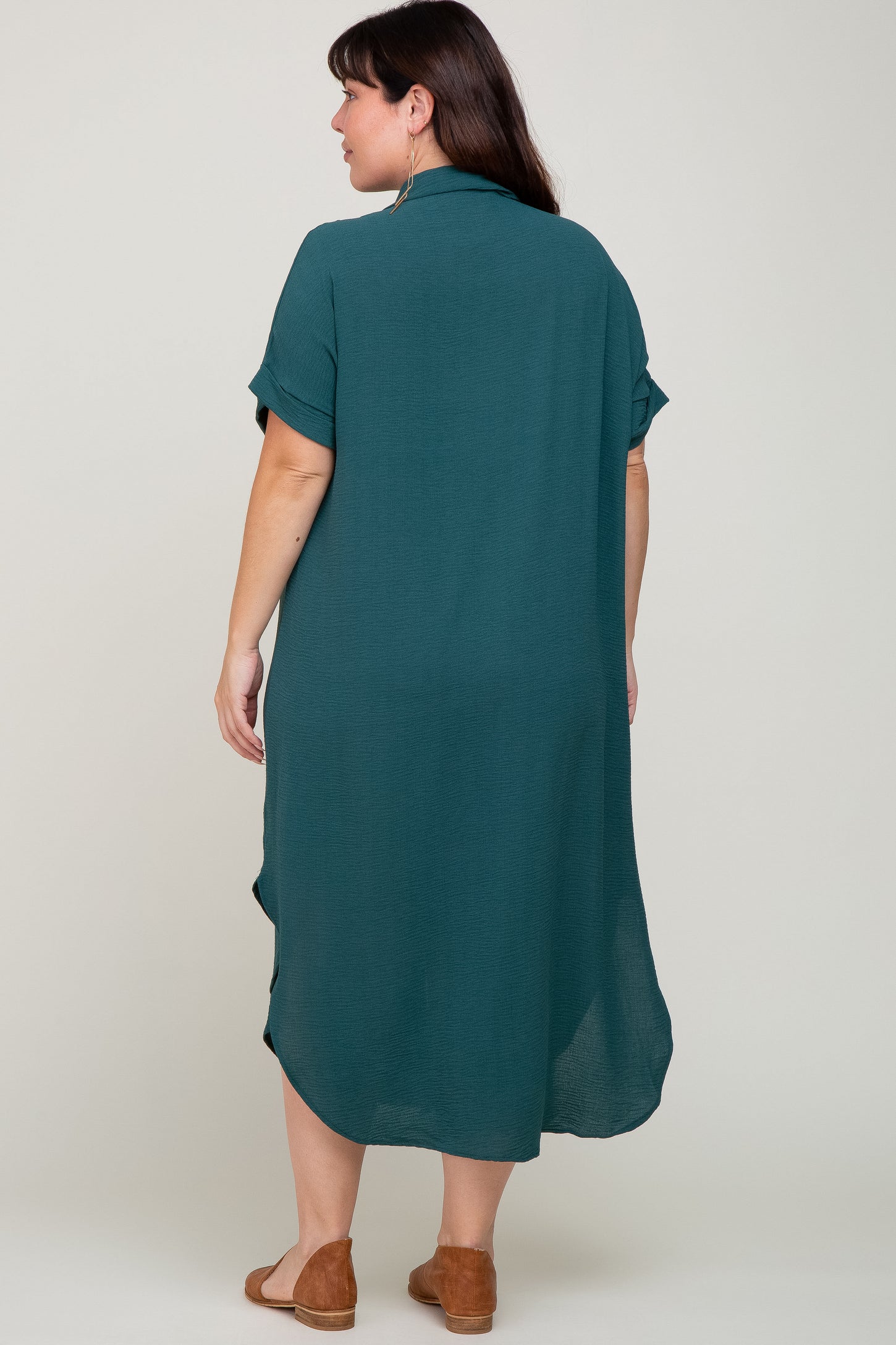 Back view of a woman wearing a short sleeve dark teal midi shirt dress with brown flats