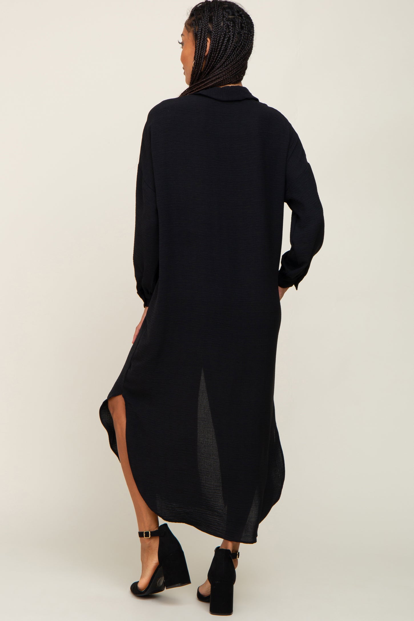 Woman from behind wearing a long black button down shirt dress and black block heel sandals