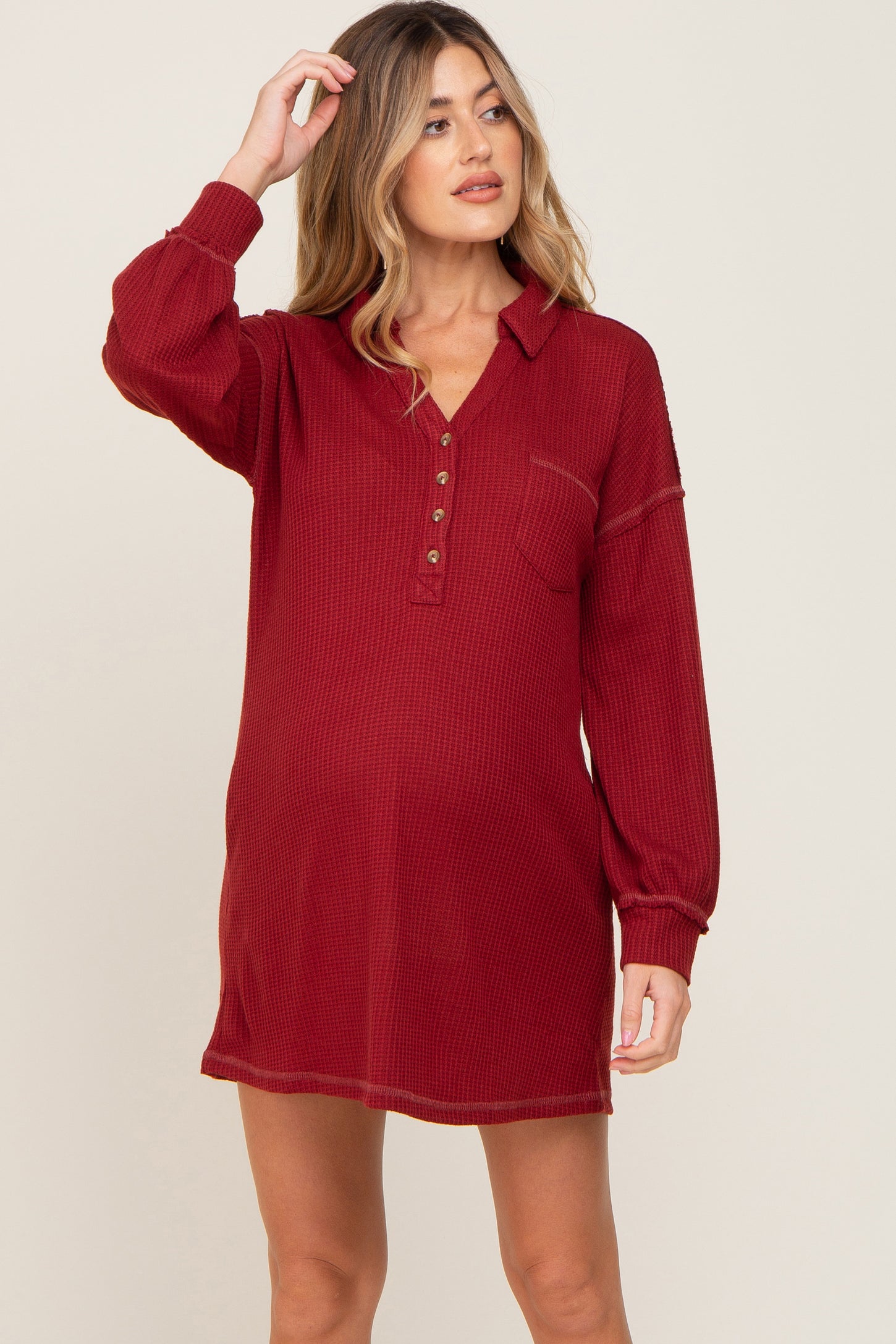 woman wearing a burgundy waffle knit long sleeve maternity tunic dress with button neckline