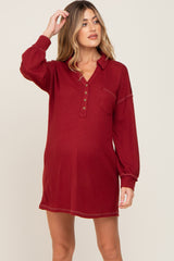 woman wearing a burgundy waffle knit long sleeve maternity tunic dress with button neckline