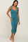 woman wearing a teal floral midi dress with tie straps and ruching, standing in a neutral background