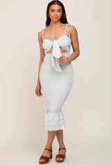 Woman wearing a light blue floral smocked midi dress with tie-front cutout and ruffled hem