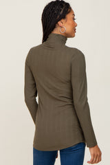 Woman wearing an olive green ribbed turtleneck long sleeve top and blue jeans viewed from the back