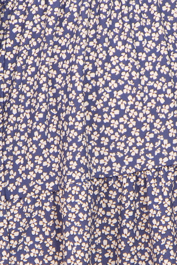 Close up of blue fabric with a white floral ditsy print and ruffled tiers