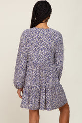Back view of a woman wearing a blue long sleeve tiered mini dress with a white floral print