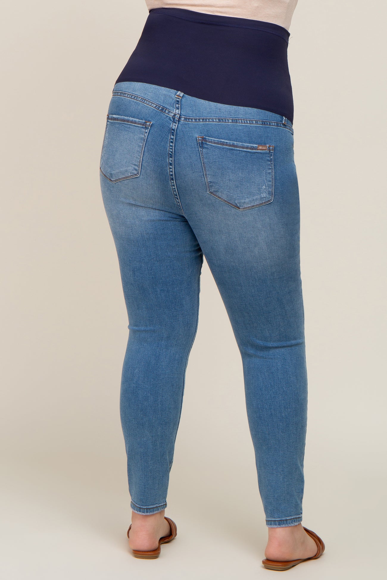 Rear view of a person wearing blue maternity skinny jeans with a navy blue over-the-belly comfort waistband