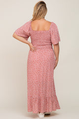 Back view of a woman wearing a pink floral smocked maternity maxi dress with short flutter sleeves