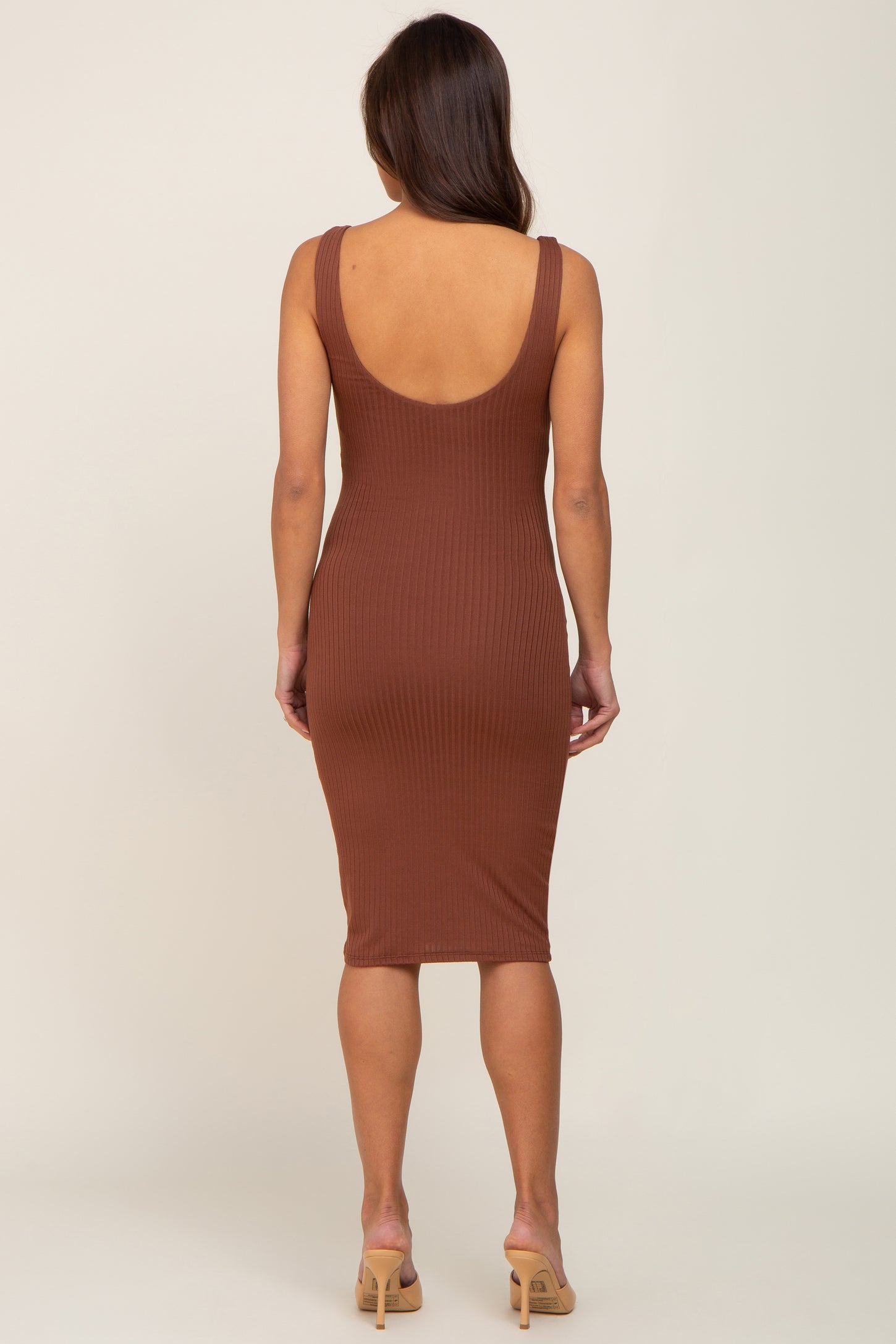 back view of woman wearing a brown ribbed midi dress with a scoop back and tan heels