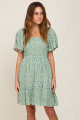 woman wearing a green floral smocked mini dress with puff sleeves and square neckline
