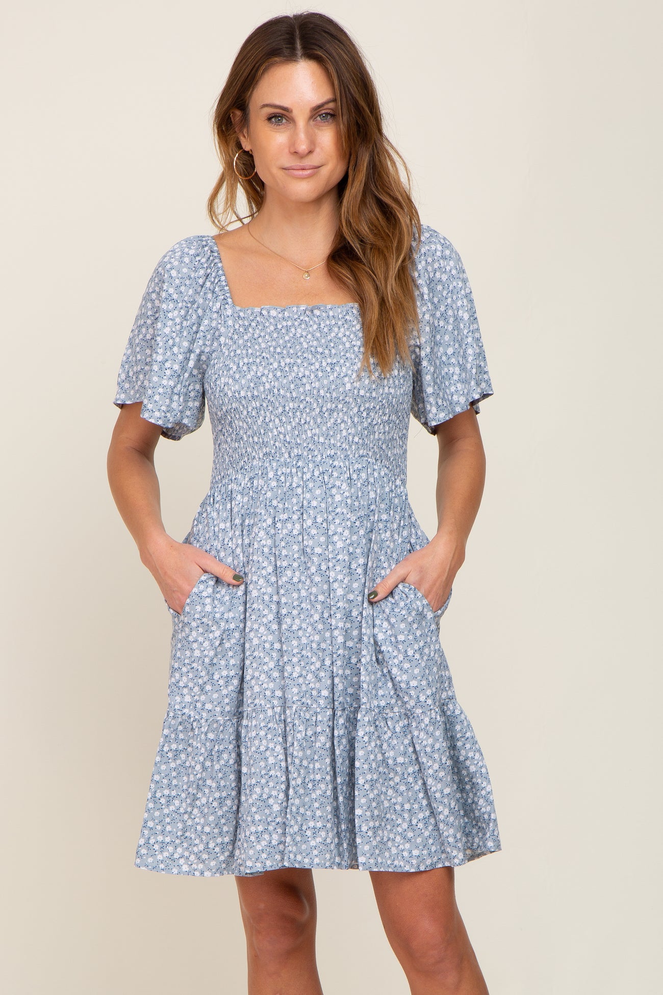woman wearing a light blue floral smocked mini dress with puff sleeves and pockets