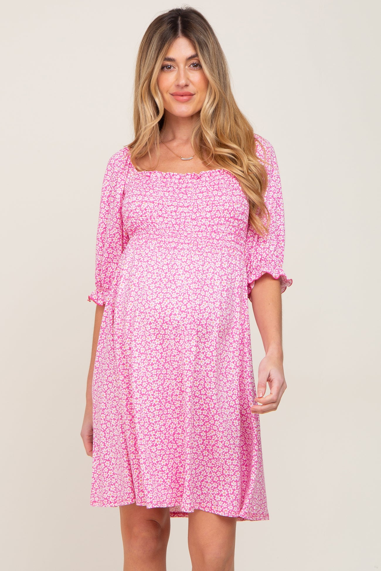 pregnant woman wearing a pink floral smocked maternity dress with puff sleeves