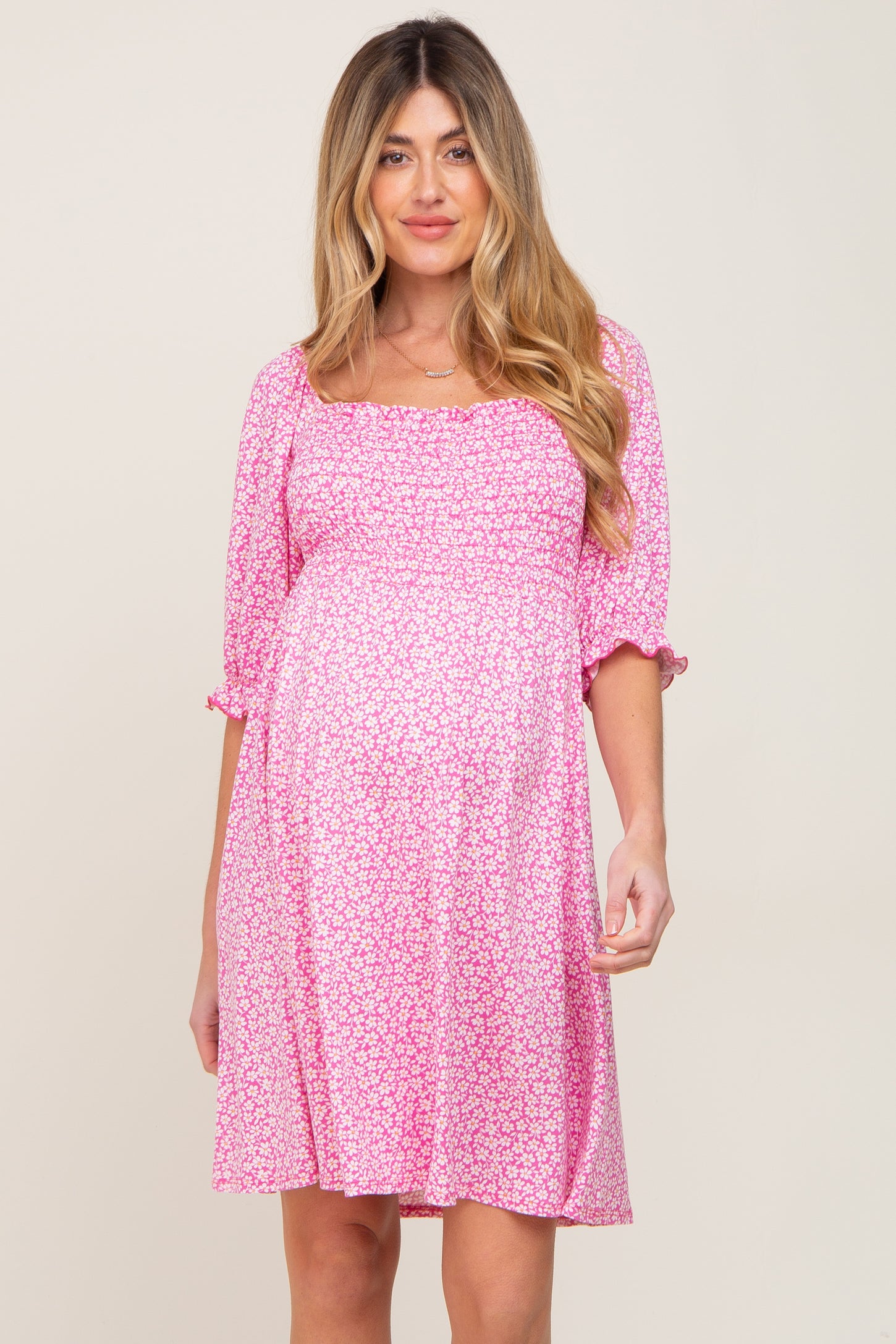 pregnant woman wearing a pink floral smocked maternity dress with puff sleeves