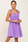 Woman wearing a purple eyelet mini dress with smocked bodice and ruffled straps