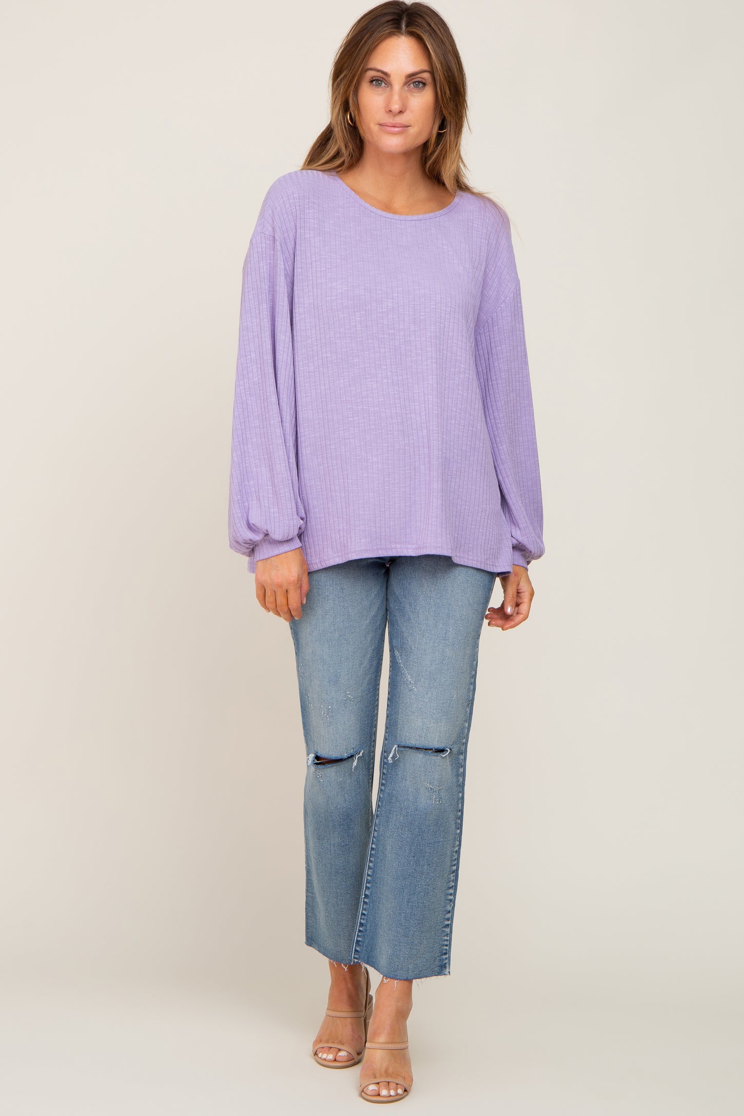 woman wearing a lavender ribbed long sleeve top and distressed light wash jeans with tan sandals
