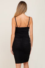 Back view of a woman wearing a black sleeveless ruched bodycon dress with thin adjustable straps