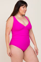 Woman wearing a bright pink one-piece swimsuit with ruched detailing and a shell necklace