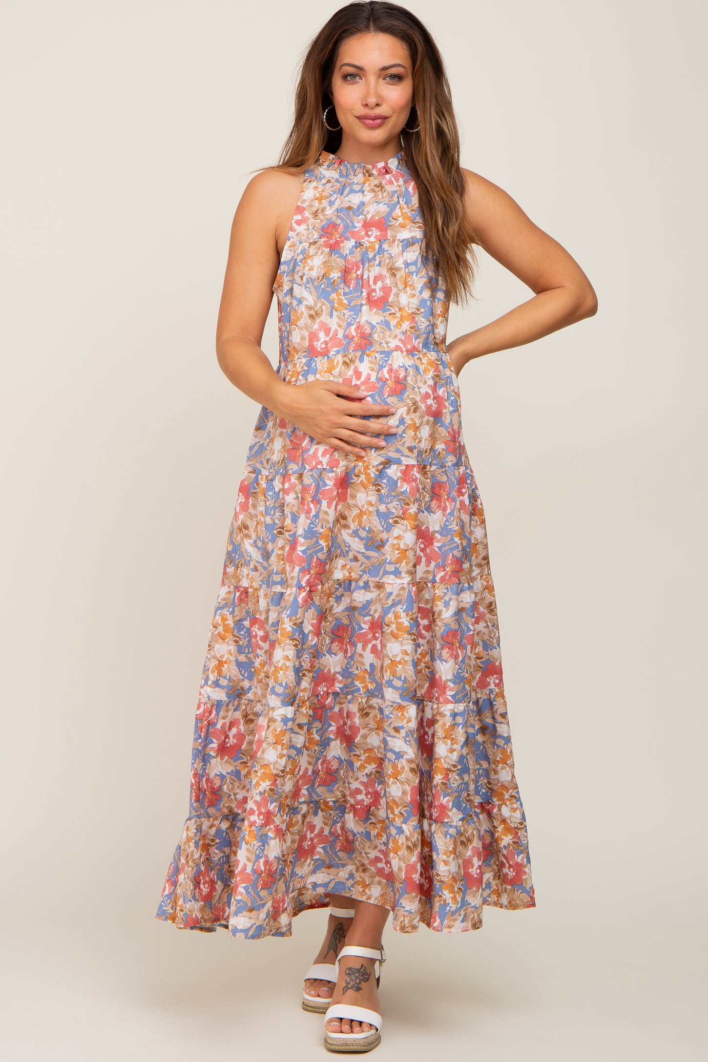 Pregnant woman in a floral halter neck tiered maternity maxi dress with blue and pink flower patterns