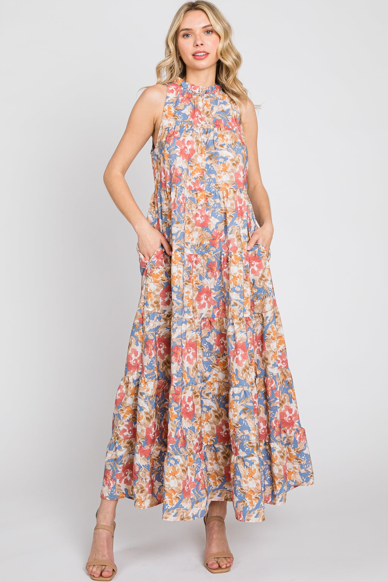 Woman wearing a sleeveless tiered floral maxi dress with pockets and high neckline