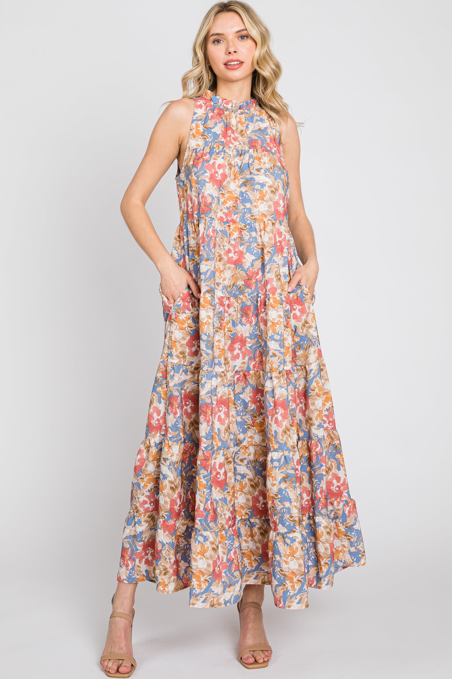 Woman wearing a sleeveless tiered floral maxi dress with pockets and high neckline