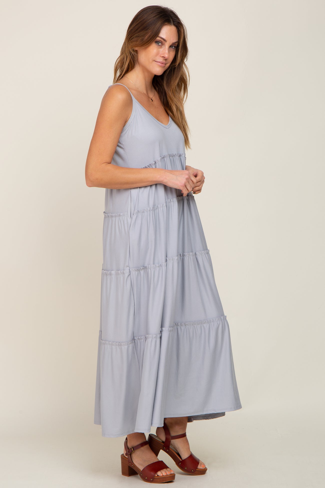 woman wearing a light blue tiered maternity maxi dress with spaghetti straps and brown platform sandals