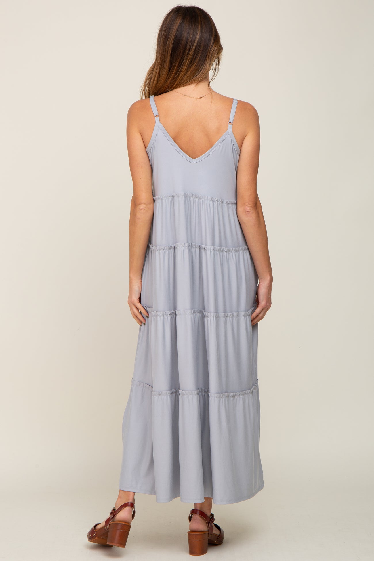 back view of woman wearing light blue tiered maxi dress with spaghetti straps and brown platform sandals