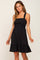 woman wearing a black smocked maternity dress with thick straps and a ruffled hem