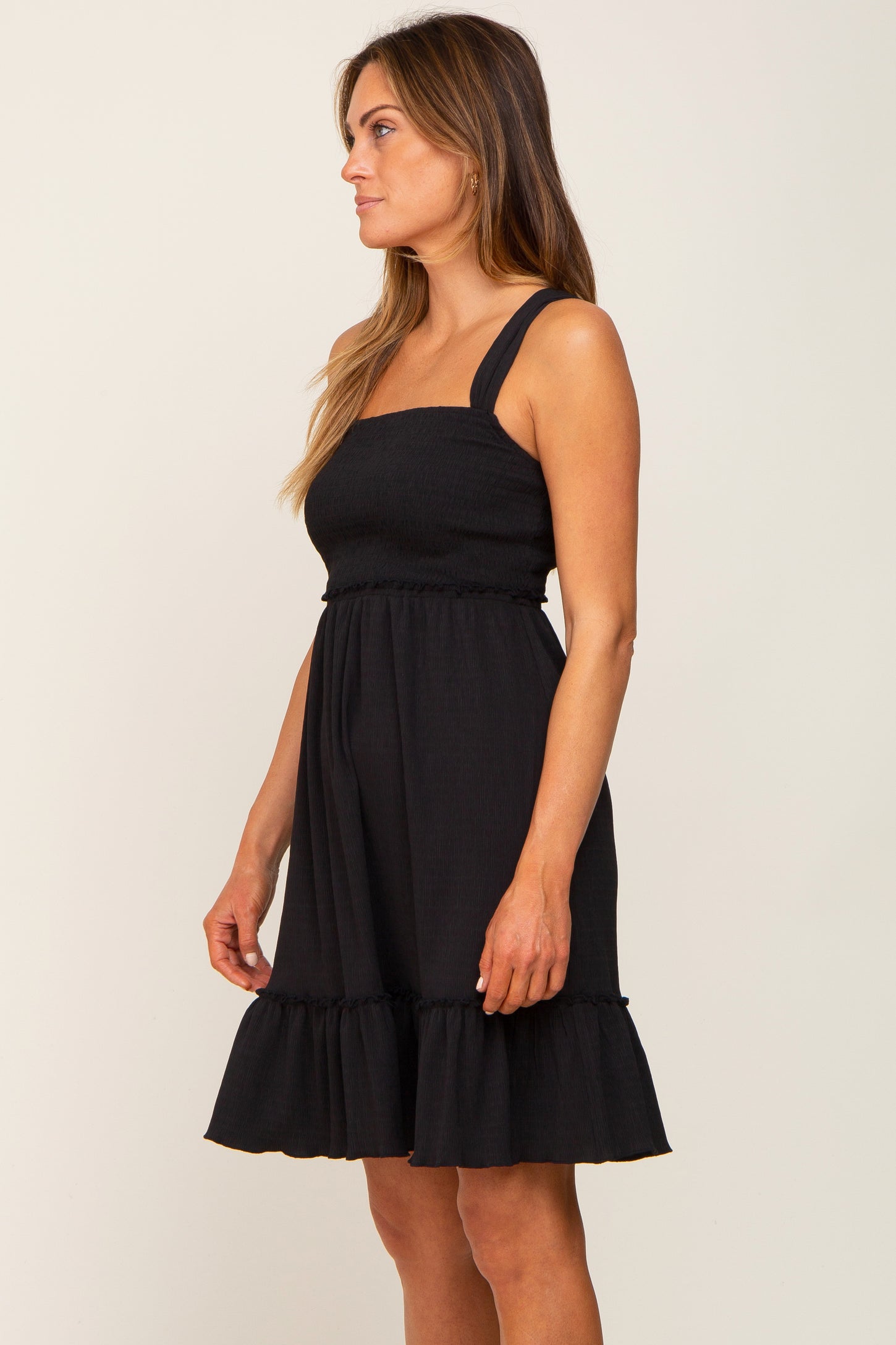 woman wearing a black smocked maternity dress with ruffle hem and square neckline