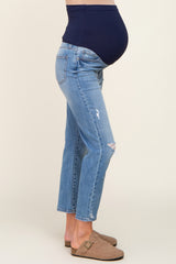 Pregnant woman wearing distressed maternity jeans with a navy blue belly band and tan suede clogs