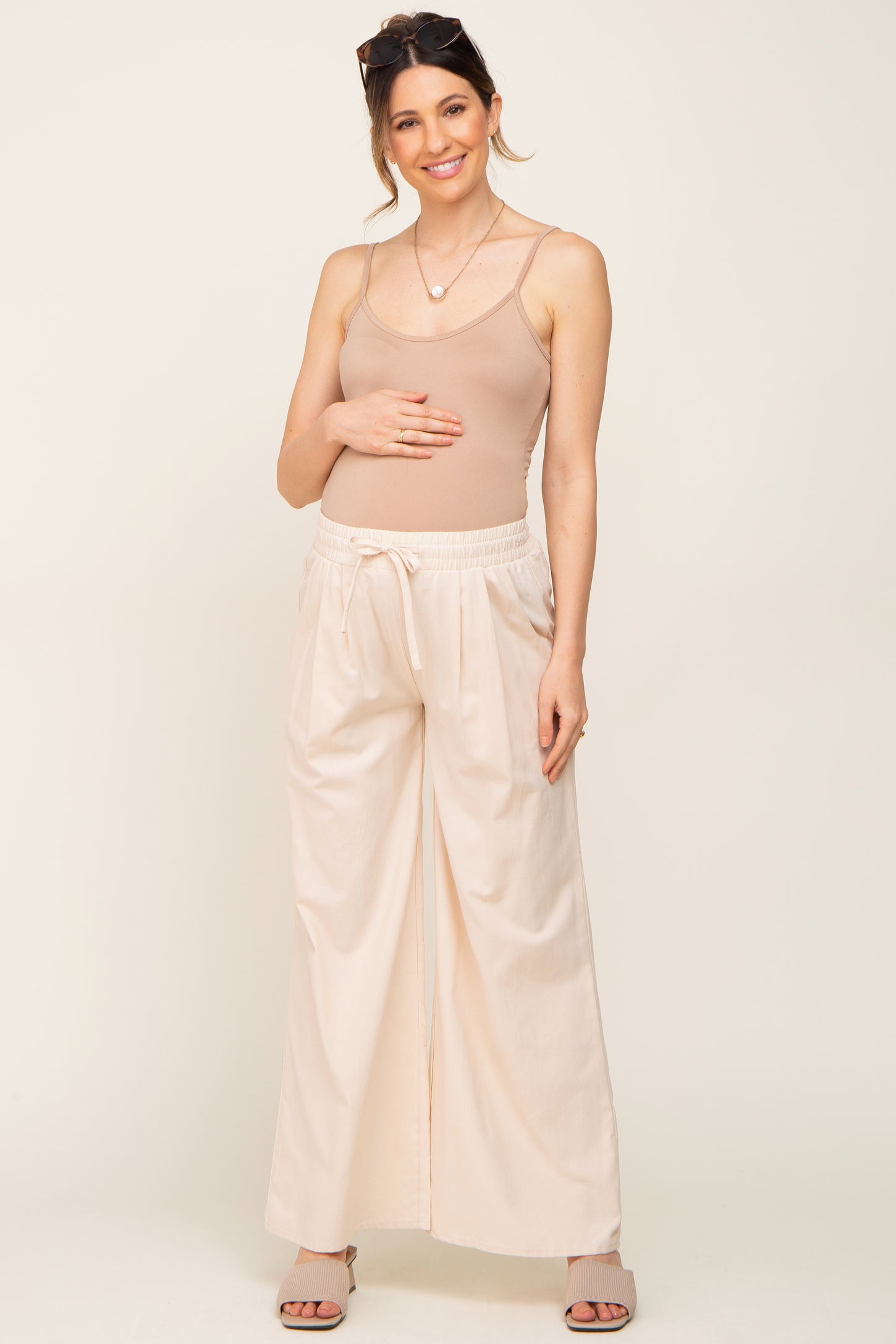 pregnant woman wearing tan maternity camisole and cream wide leg drawstring pants