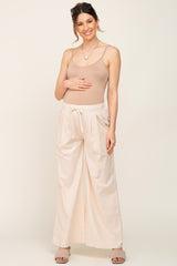 pregnant woman wearing tan maternity camisole and cream wide leg drawstring pants