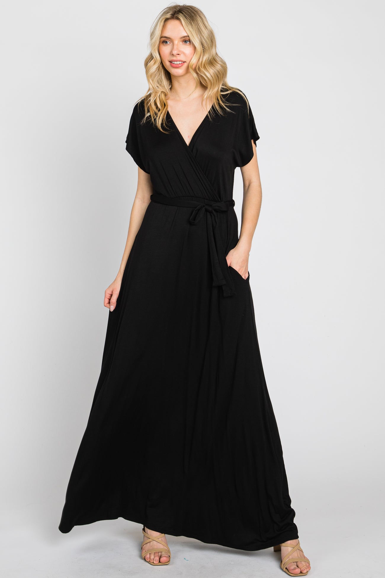 Woman wearing a black short sleeve wrap maxi dress with a waist tie and pockets