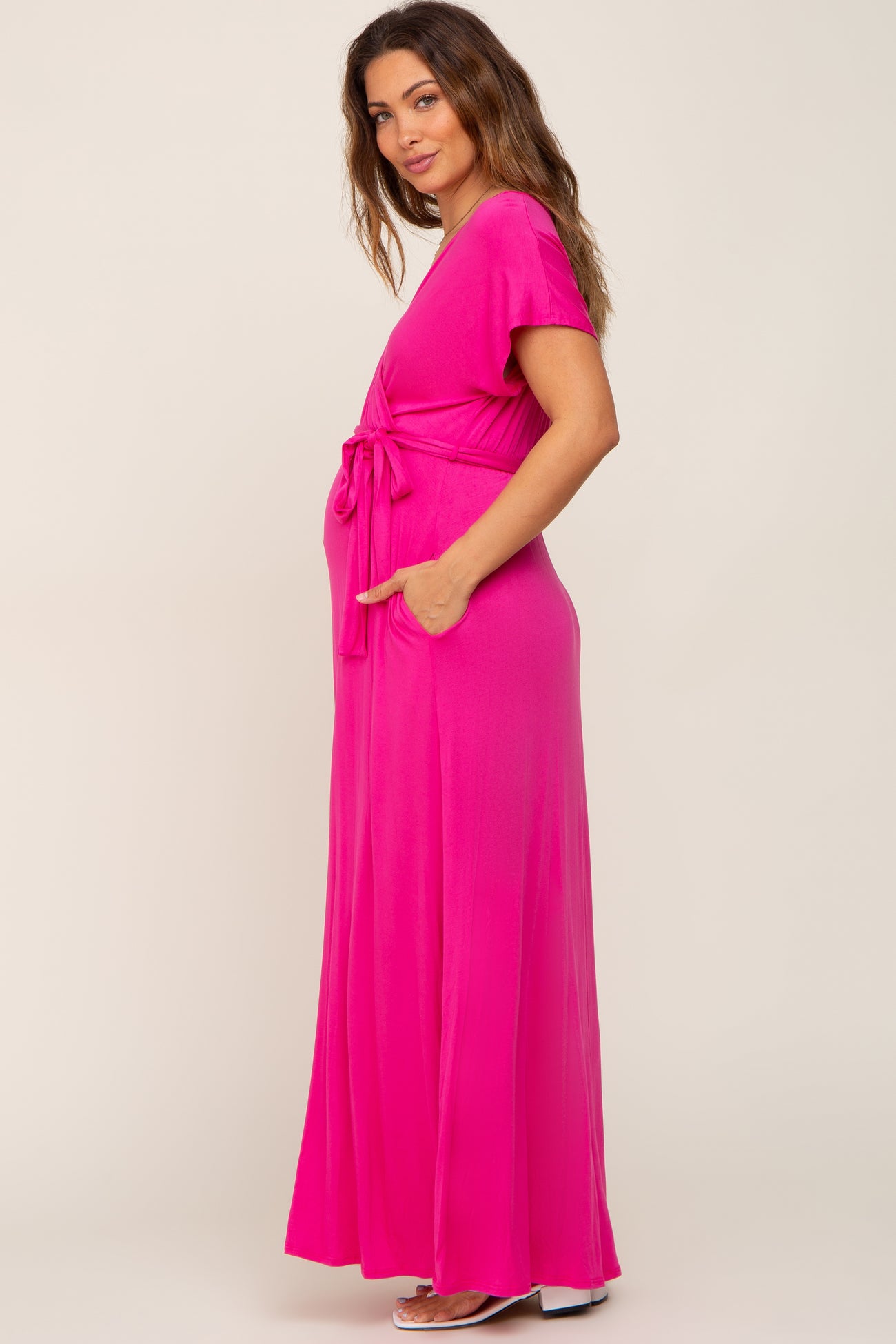 Pregnant woman wearing a hot pink short sleeve maternity maxi dress with a waist tie and pockets
