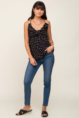 woman wearing black floral ruffle maternity tank top and blue skinny jeans