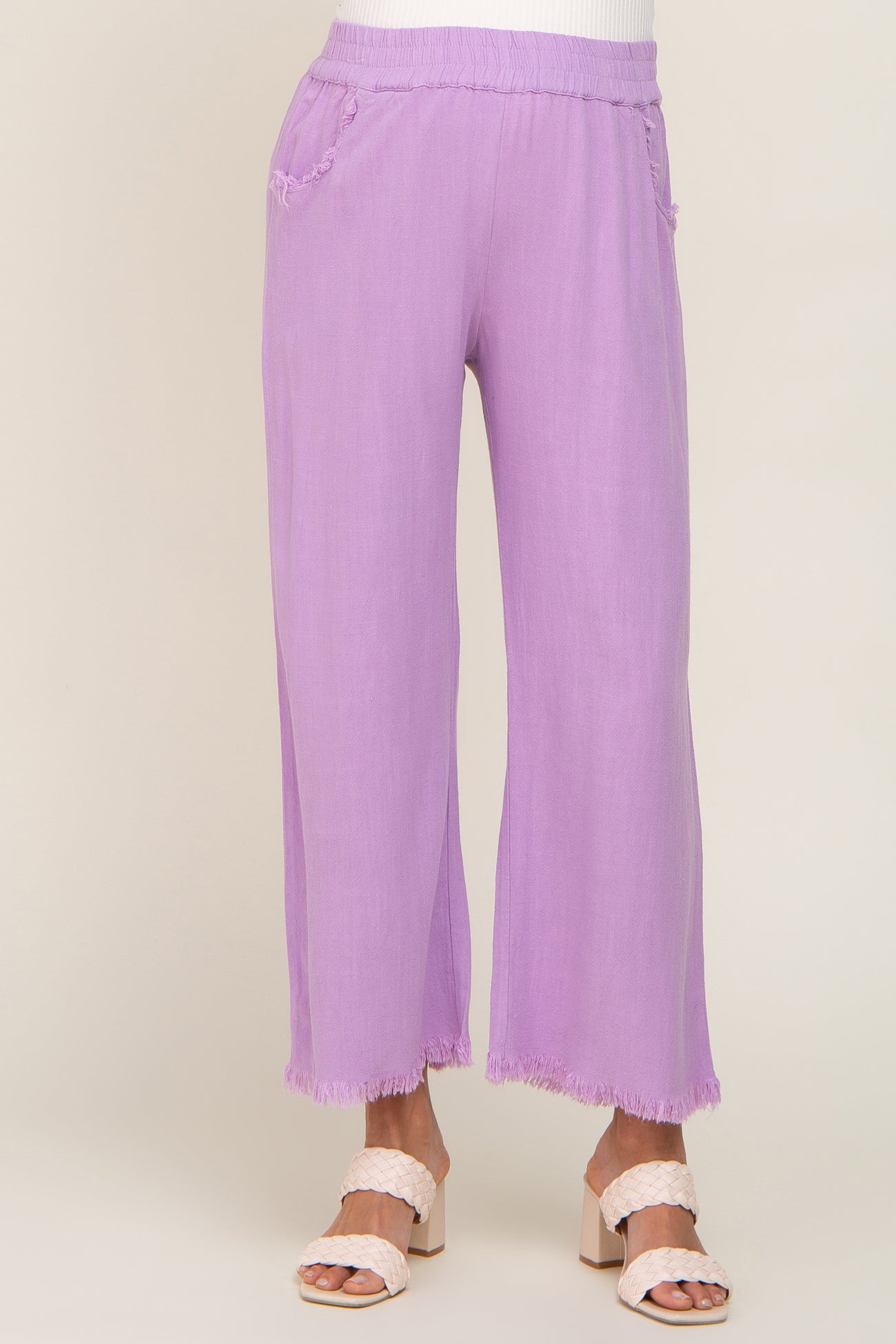 woman wearing lavender wide leg pants with frayed hem and elastic waistband paired with cream woven heels