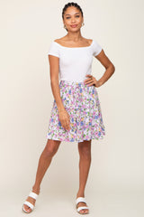woman wearing white off-the-shoulder top and lavender floral tiered mini skirt with white slide sandals
