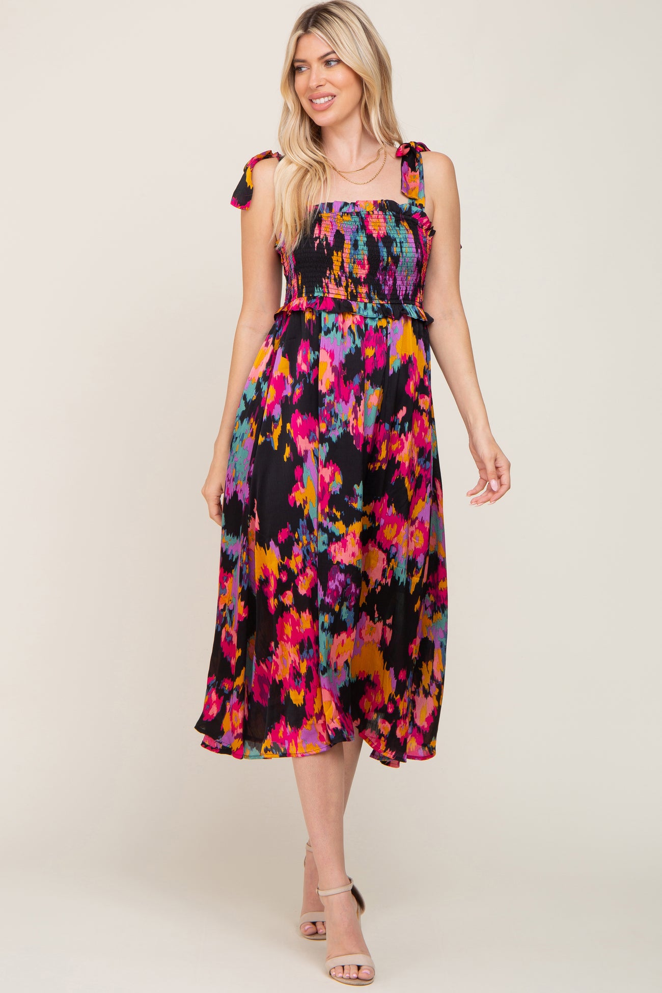 woman wearing a colorful abstract print midi dress with smocked bodice and tie straps